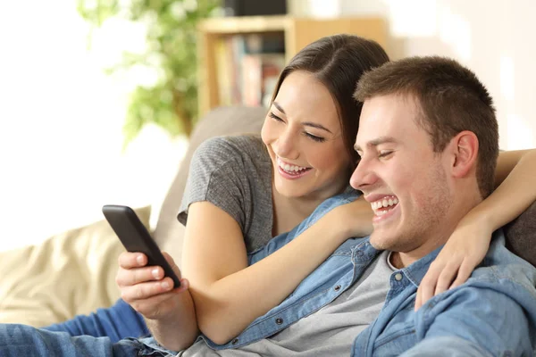 Пара смеющихся, смотрящих медиа контент в телефоне — стоковое фото