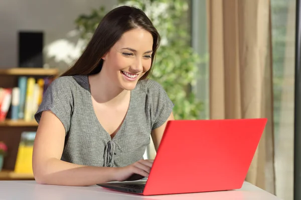 Författare som skriver i en röd laptop hemma — Stockfoto