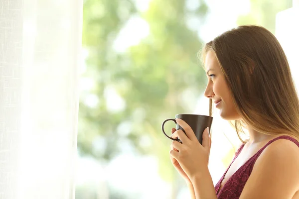 Mujer pensativa relajándose mirando a través de una ventana — Foto de Stock