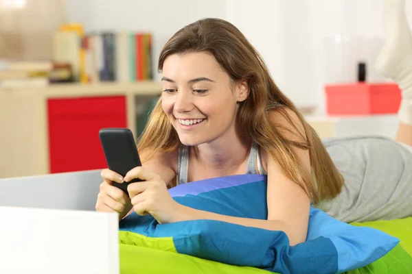 Adolescente ler mensagens no telefone na cama — Fotografia de Stock