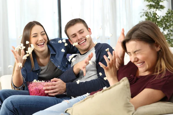 Happy friends joking throwing popcorn — Stock Photo, Image