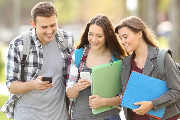 Tři studenti kontrolu chytré telefony — Stock fotografie