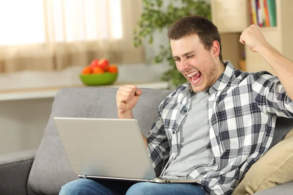Homme excité en ligne avec un ordinateur portable à la maison — Photo