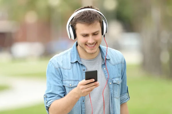 Tiener jongen wandelen en luisteren op lijn muziek — Stockfoto