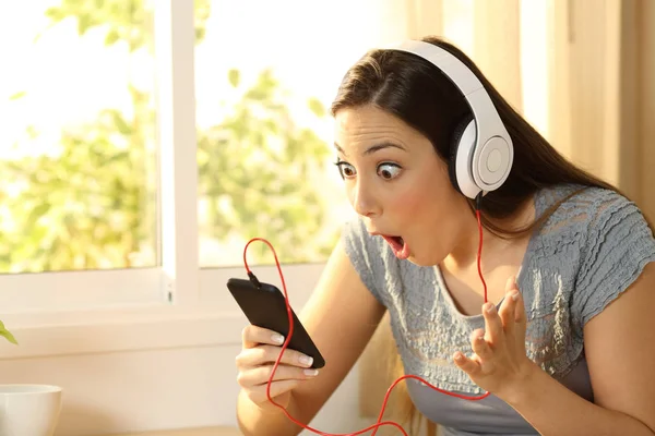 Mujer sorprendida escuchando música encontrar oferta — Foto de Stock