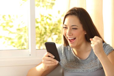 Kadın akıllı telefon üzerinde içerik izlerken heyecanlı