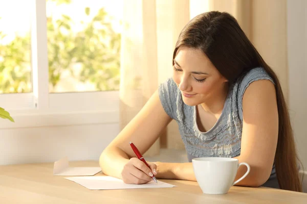 Menina escrevendo uma carta em uma mesa — Fotografia de Stock