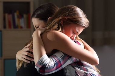 Two sad teens embracing at bedroom clipart