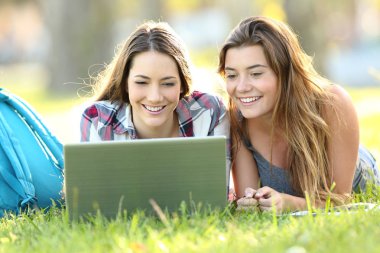 İki öğrenci satırındaki laptop ile içerik izlerken