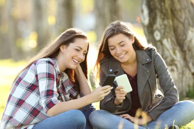 İki arkadaş akıllı telefonlarını medyada izlerken