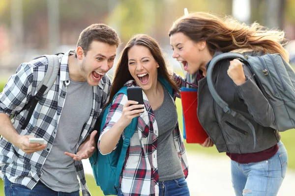 Excited students receiving good news on phone — Stock Photo, Image