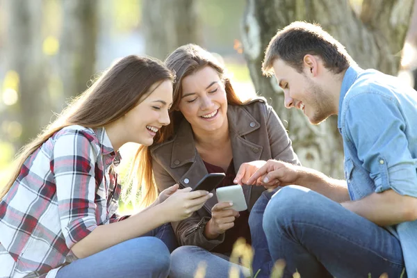 Three teens sharing on line content on phones — Stock Photo, Image