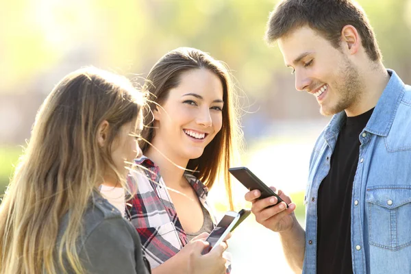 Teens using smart phones and one looking at you — Stock Photo, Image