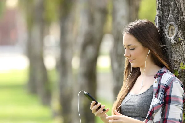 Menina relaxada ouvindo música em um parque — Fotografia de Stock