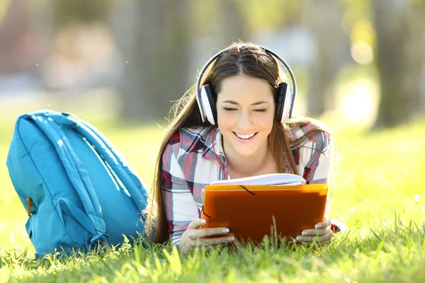 Estudiante leyendo notas y escuchando un audio tutorial —  Fotos de Stock