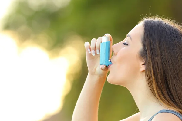 Женщина, использующая ингалятор от астмы на открытом воздухе — стоковое фото