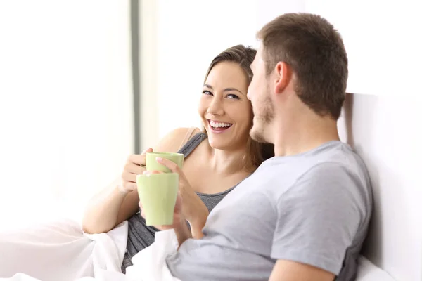 Casal tomando café da manhã e falando em uma cama — Fotografia de Stock