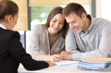 Happy couple signing a contract at office clipart