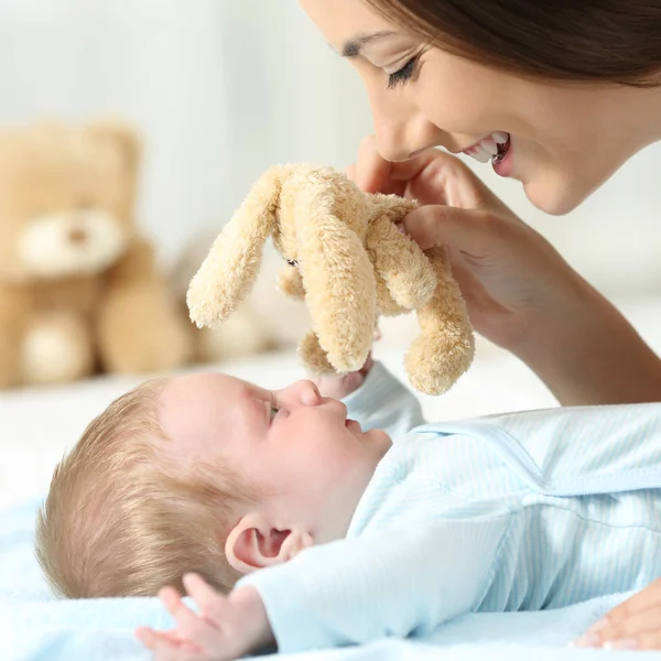 Mãe brincando com seu bebê com um ursinho — Fotografia de Stock