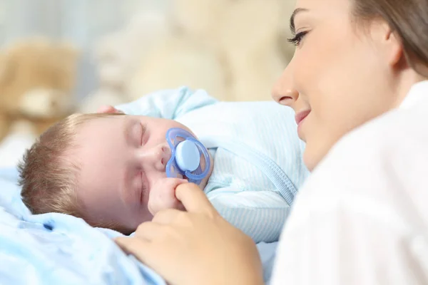 Mamma titta på hennes baby som sover på säng — Stockfoto