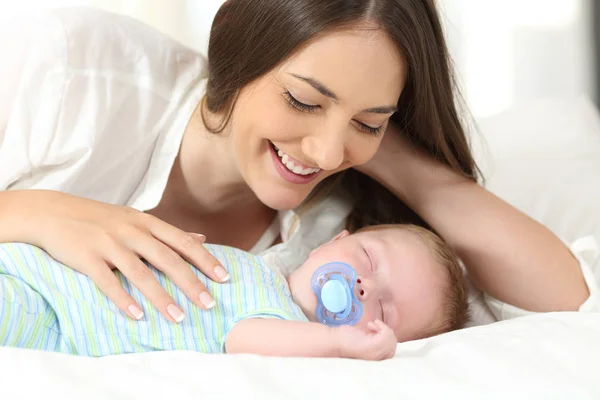 Mãe assistindo seu bebê dormindo em uma cama — Fotografia de Stock