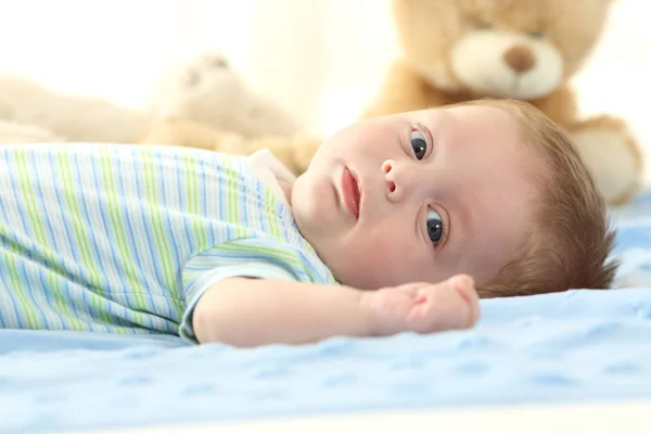 Bambino sdraiato su un letto e guardandoti — Foto Stock