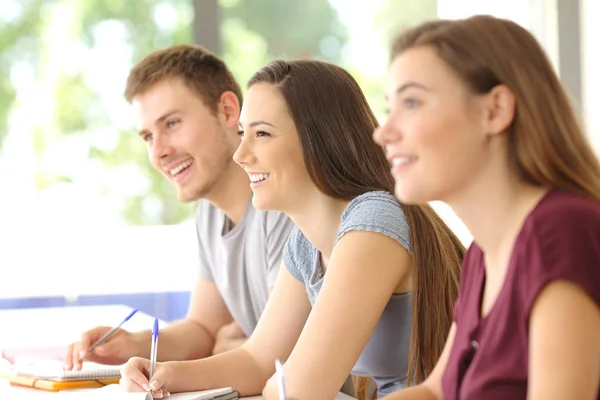 Drie studenten luisteren in een klaslokaal — Stockfoto