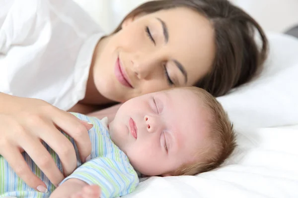 Mother and baby sleeping together on bed Royalty Free Stock Photos