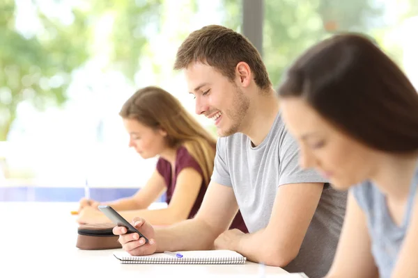 Student roztržitý s mobilním telefonem v učebně — Stock fotografie