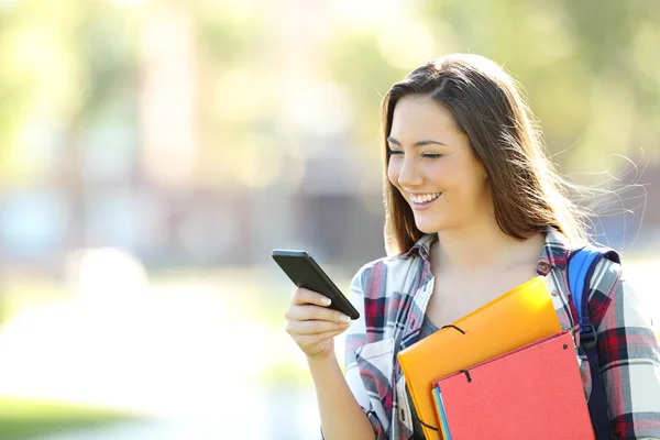 Estudante feliz andando e usando um telefone celular — Fotografia de Stock