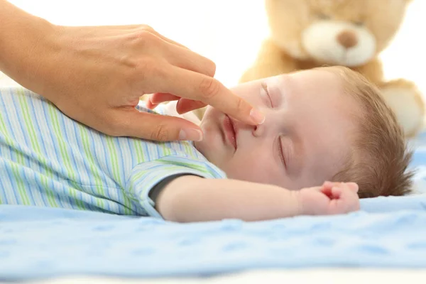 眠っている赤ちゃんの鼻に触れる母の手 — ストック写真