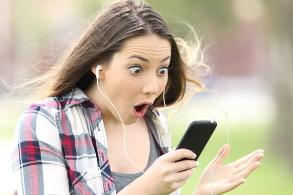 Chica sorprendida escuchando música en línea — Foto de Stock