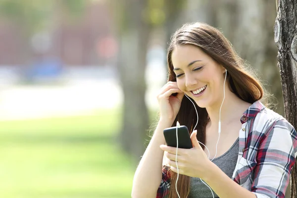 Glad tjej lyssnar på linje musik i en park — Stockfoto