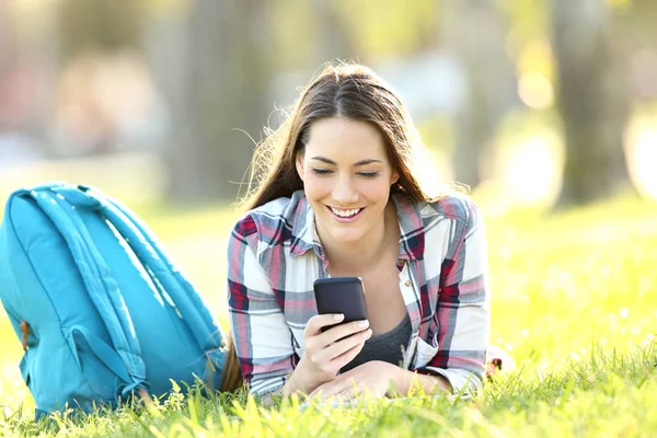 Счастливый студент переписывается по мобильному телефону — стоковое фото