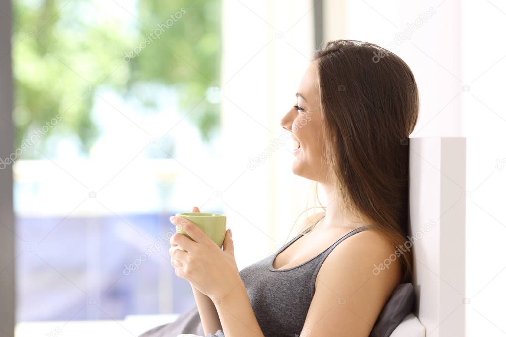 Happy woman having breakfast on the bed
