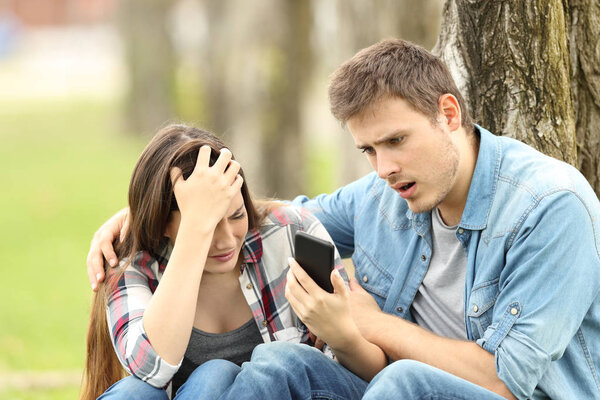 Sad woman shows message to a surprised friend