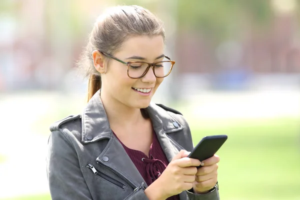 Flickan bär glasögon SMS i mobiltelefonen — Stockfoto