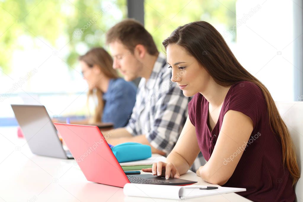 Three students studying on line in a classroom