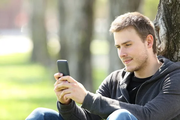 Garçon lisant des messages dans un téléphone intelligent à l'extérieur — Photo