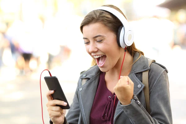 Entusiasmado adolescente ouvir música em um telefone — Fotografia de Stock