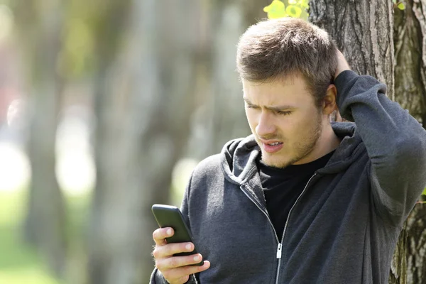 Zmatený teen čtení zprávy v chytrý telefon — Stock fotografie