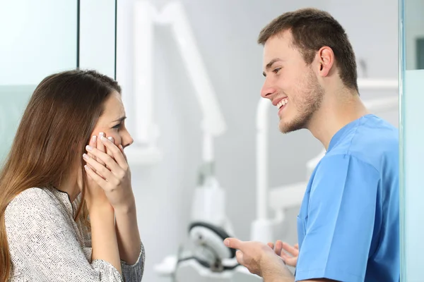 Пациент с зубной болью жалуется дантисту — стоковое фото