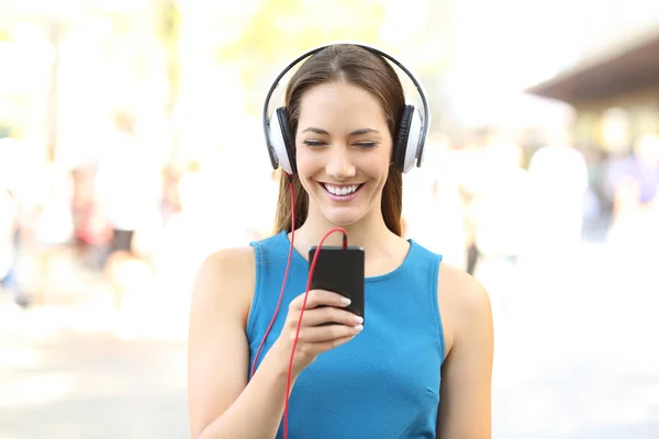 Framsida av en flicka som lyssnar på musik på gatan — Stockfoto