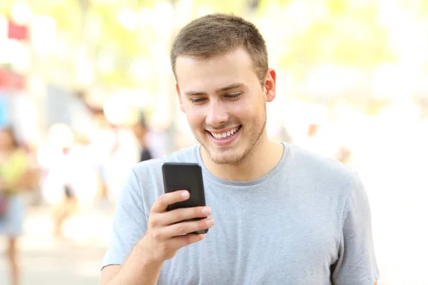 Guy using a smart phone walking on the street — Stock Photo, Image