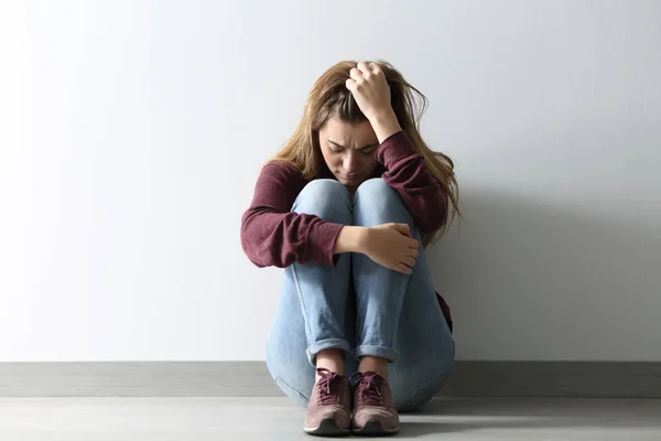 Front view of a sad woman sitting on the floor — Stock Photo, Image