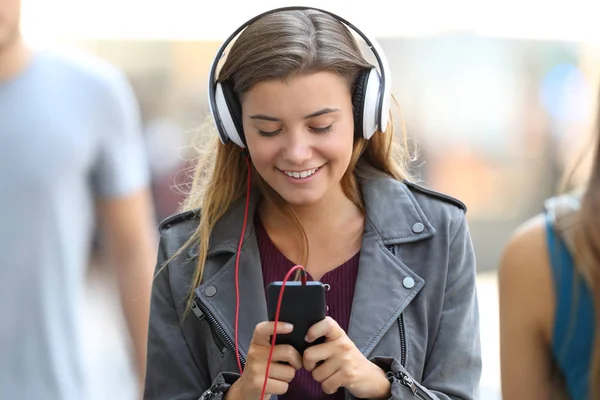 Girl listening to music and walking on the street — Stock Photo, Image