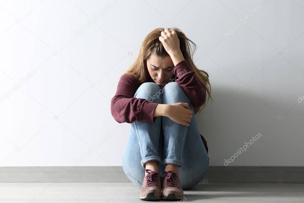 Front view of a sad woman sitting on the floor