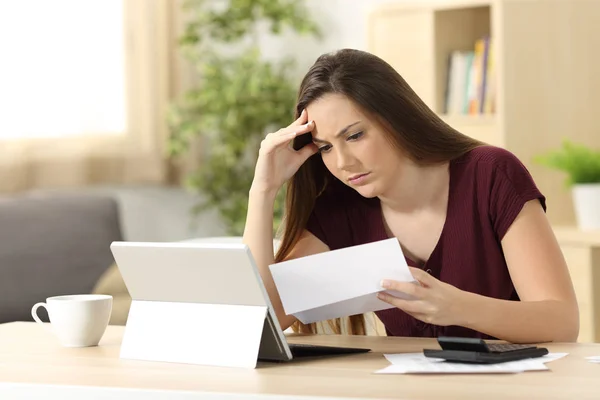 Беспокойная женщина, рассчитывающая бухгалтерию, читая письмо — стоковое фото