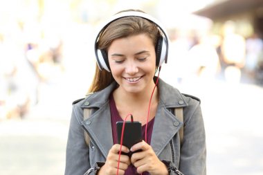 Gülümseyen genç bir akıllı telefon üzerinde müzik dinleme