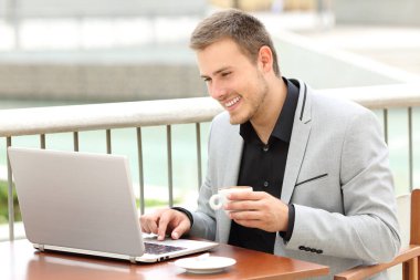 Bir kahve dükkanında bir dizüstü bilgisayar kullanarak gülen icra